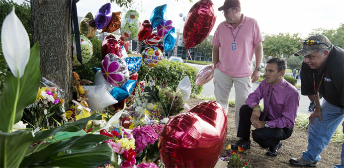 WDBJ TV  weatherman Leo Hirshbrunner(C) views the makeshift memorial with members of the crew at the gate of WDBJ's television studios 