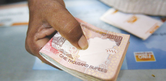 A customer hands a bundle of Indian rupee notes to a teller at a financial institution in Mumbai. The rupee weakened 0.9% to Rs60.22 per dollar in Mum