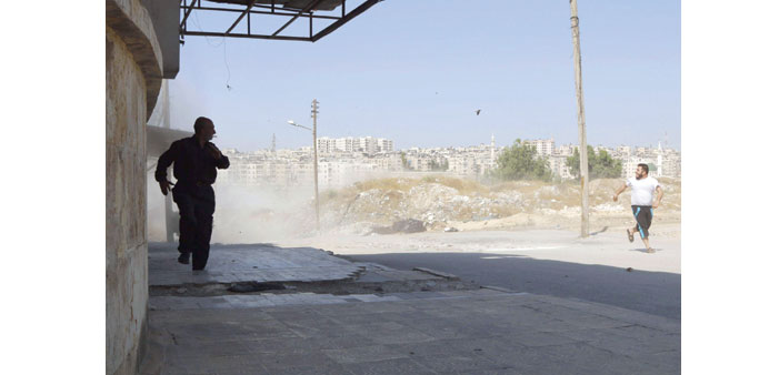 People run at a site hit by what activists said was a barrel bomb dropped by regime forces in the Al Kalaset district of Aleppo yesterday.