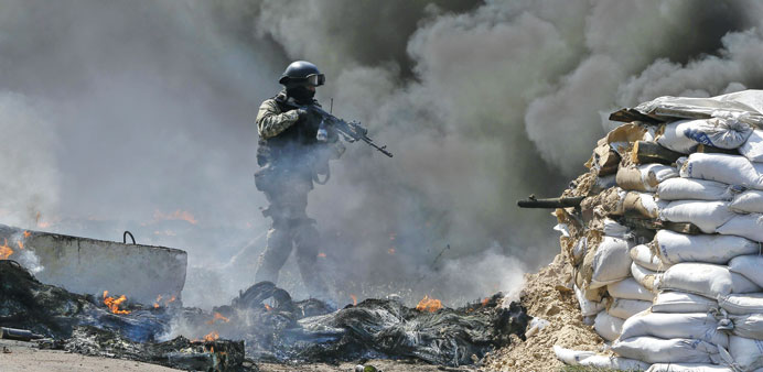 A Ukrainian soldier takes up a position at a checkpoint set on fire and left by pro-Russian separatists near Slaviansk.