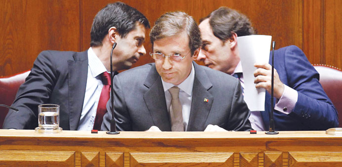 Portas (right) is seen talking with Gaspar (left) behind Prime Minister Passos Coelho during a debate at parliament in Lisbon, in this June 25, 2012 f