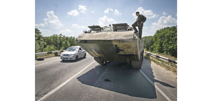 A pro-Russian separatist stands guard atop an amphibious vehicle near a checkpoint outside Luhansk.
