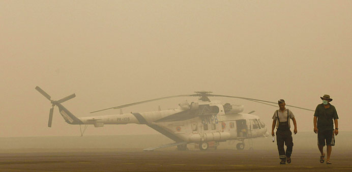 A helicopter crew deployed for water bombing walk past their grounded aircraft due to thick haze in Palembang on Sumatra island.