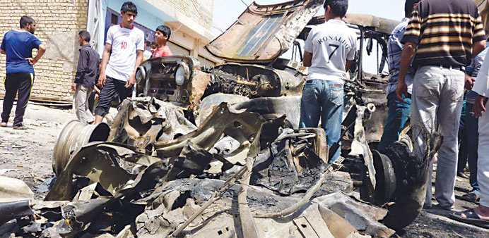 Schoolboys look at the remains of vehicles damaged following an explosion in the Al Obaidi neighbourhood, east of Baghdad yesterday.
