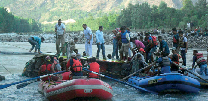 Volunteers and police personnel attempt to reach victims inside a partially submerged bus that tumbled into the Beas river in Kullu yesterday.