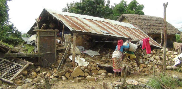 A Nepalese family collect a bag of grains from their damaged house after floods in the Tharu village of Hatipur in Surkhet district, some 400km west o