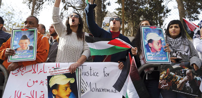 Palestinians protest outside the Jerusalem district court yesterday during the trial of three Israelis over the murder of Palestinian teenager Mohamed