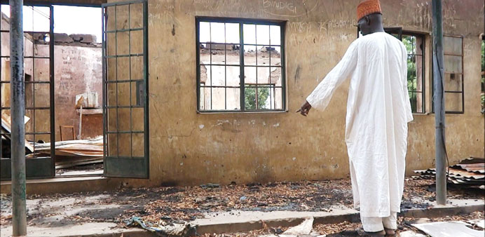 This picture taken on August 6, 2013, of an employee inspecting a blown-up students hostel in the Government Secondary School of Mamudo, in the northe
