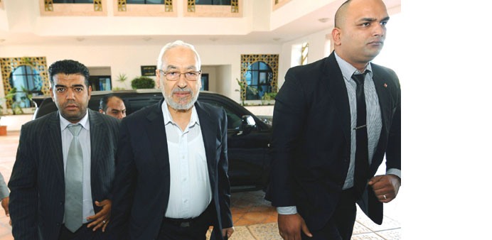    Ennahdha leader Rached Ghannouchi arrives with his bodyguards for the talks between ruling Islamists and the opposition in Tunis yesterday.