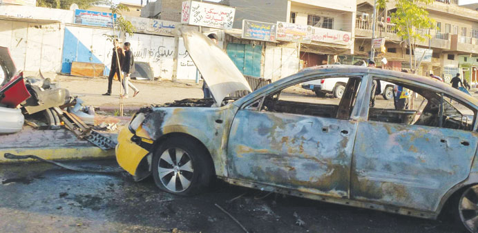 People walk at the scene of a car bomb attack in Bayaa district, eastern Baghdad, yesterday. 