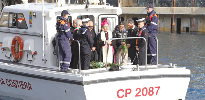 A senior clerical figure says prayers aboard an Italian coastguard ship before a wreath was thrown into the sea in a ceremony in Giglio Porto to mark 