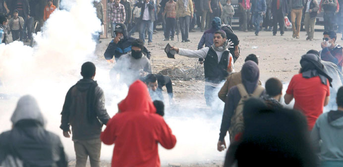 Protesters flee from teargas fired by riot police during clashes in Cairo yesterday. 