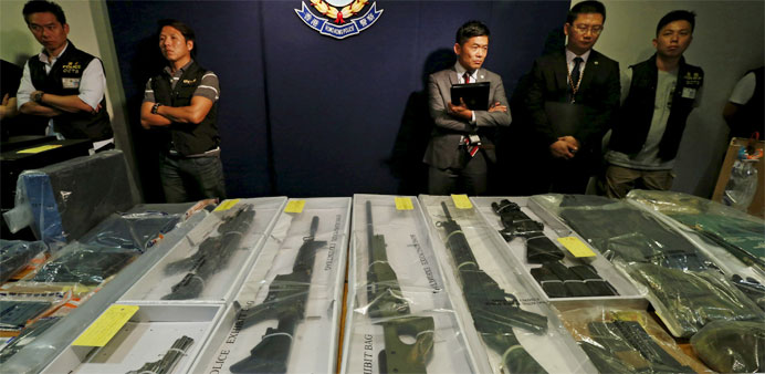 Police officers stand in front of air rifles seized along with explosives