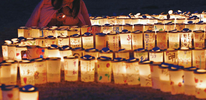 A girl lights candles during a memorial in remembrance of victims of the Fukushima disaster in Iwaki on March 9, 2014.