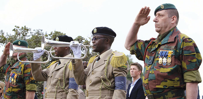 A Belgian soldier salutes while his Rwandan counterparts blow bugles during a memorial service yesterday for 10 Belgian commandos killed at the onset 
