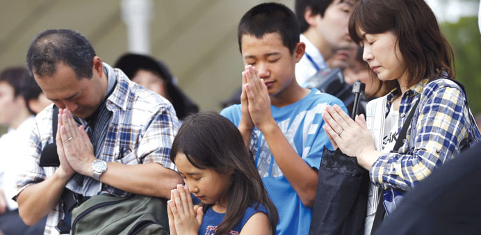 A family prays for victims of the 1945 atomic bombing in front of the Peace Statue before a ceremony commemorating the 70th anniversary of the bombing