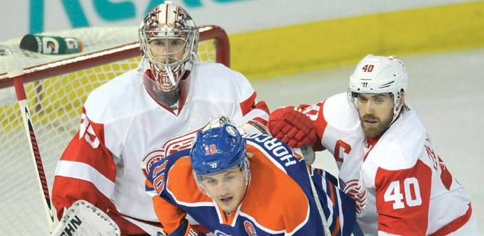 Edmonton Oilersu2019 Shawn Horcoff (centre) is checked by Detroit Red Wingsu2019 goalie Jimmy Howard (left) and Henrik Zetterberg during the first period of t