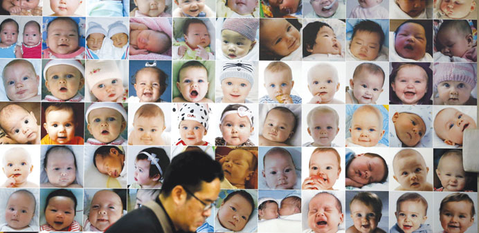 A man uses his mobile phone next to portraits of babies used as advertisement at a fertility and genetic clinic in Bangkok.