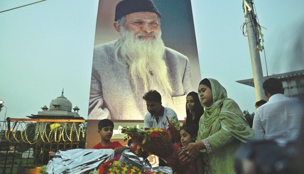 People placing flowers in front of a portrait of  Abdul Sattar Edhi in Islamabad yesterday.