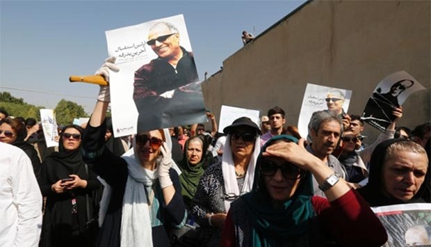 Iranians hold posters bearing a portrait of Iranian film-maker Abbas Kiarostami during a ceremony in Tehran ahead of his funeral in the town of Lavasan on Sunday.