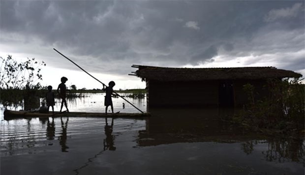 Indian children paddle a raft near their partially submerged house in the flood-affected Mayong village in the Morigoan district of Assam.