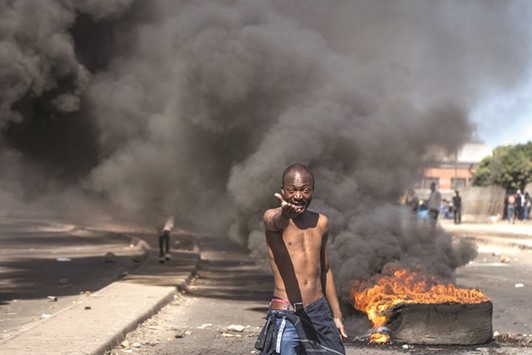 A protester shouting anti-Mugabe slogans in front of burning tyres during a demonstration on July 6, in Makokoba, Bulawayo Zimbabwe.