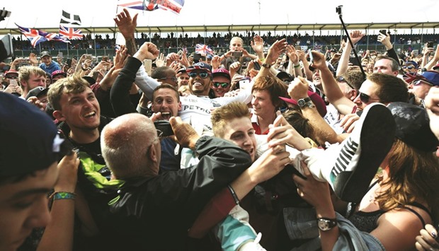 Mercedes driver Lewis Hamilton crowd-surfs with the fans after winning the British Grand Prix at Silverstone motor racing circuit in Silverstone, England, yesterday. (AFP)