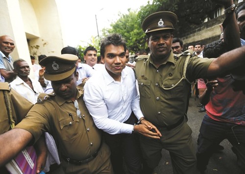 Namal Rajapakse, centre, leaving with prison officers at the court after being arrested in Colombo.