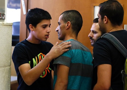 Ahmed Manasra (left), a 14-year old Palestinian boy, convicted of the attempted murder of two Israelis in a stabbing in October, kisses his father before a new hearing at the District Court in Jerusalem yesterday.