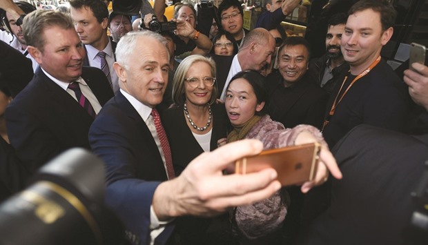 Turnbull and his wife Lucy pose for selfies yesterday during a street walk to meet voters on the eve of Australiau2019s federal elections in Sydney.