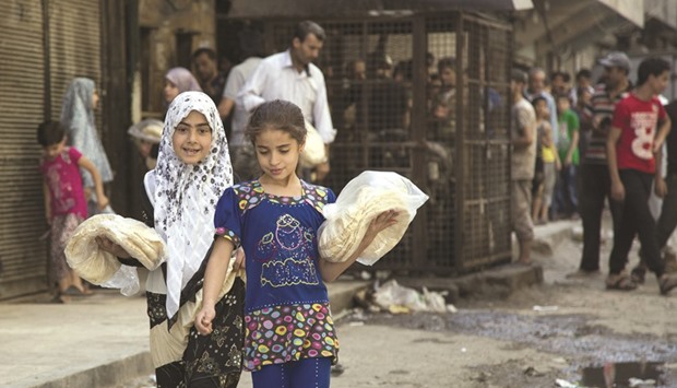 Syrian girls carry bags with bread as people queue up outisde a bakery in a rebel held neighbourhood in the northern city of Aleppo on Tuesday.