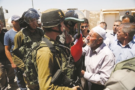 A Palestinian man argues with an Israeli soldier as he tries to prevent an Israeli excavator from clearing his land during a protest against Jewish settlements, near the village of Deir Qaddis near the West Bank city of Ramallah.