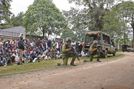 Civilians watch as police officers hold their position during an operation against a suspected Shebaab recruiter at the Kapenguria police station.