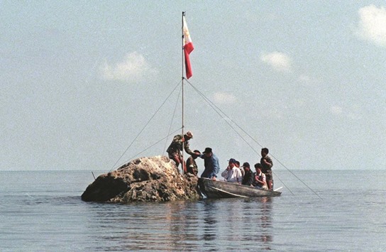 This photo taken on May 17, 1997 shows a team of Philippine Navy personnel and three congressmen from the house committee on inter-parliamentary relations and diplomacy landing at the tiny rock of Scarborough Shoal, bearing the Philippine flag that was earlier planted by Filipino fishermen.