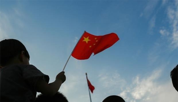 A child waves a Chinese flag during the daily flag lowering ceremony at sunset in Beijing's Tiananmen Square. The Philippines has urged Beijing to respect an international tribunal's ruling on the South China Sea.