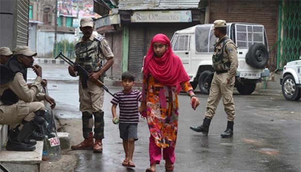 Kashmiri Muslims walk past Indian paramilitary troopers standing guard during a curfew in downtown Srinagar on Friday.