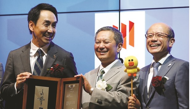 Line Corp CEO Takeshi Idezawa (left) poses as he holds an IPO certificate with Takuo Tsurushima, president of the Tokyo Stock Exchange (centre) during a ceremony to mark the companyu2019s debut on the Japanese bourse yesterday.