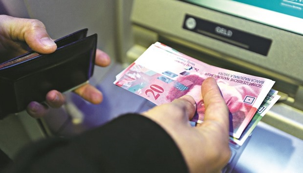 A customer collects Swiss franc banknotes from an automated teller machine in Zurich. The franc was trading around 1.09 per euro yesterday, not much changed from before the Brexit vote.