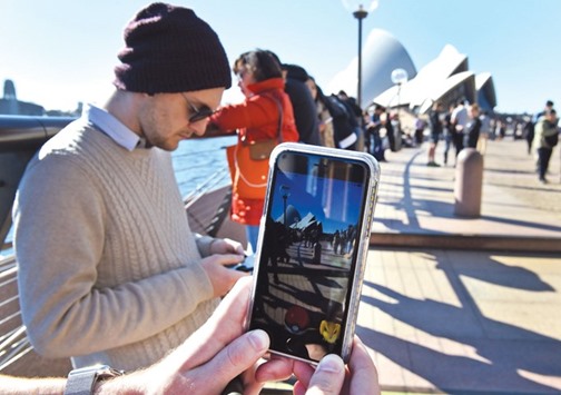 Dozens of people gather yesterday to play Pokemon Go in front of the Sydney Opera House.