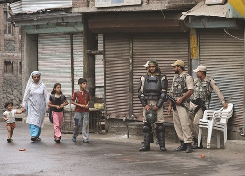 A Kashmiri family walks past paramilitary troopers standing guard during a curfew, in downtown Srinagar yesterday.