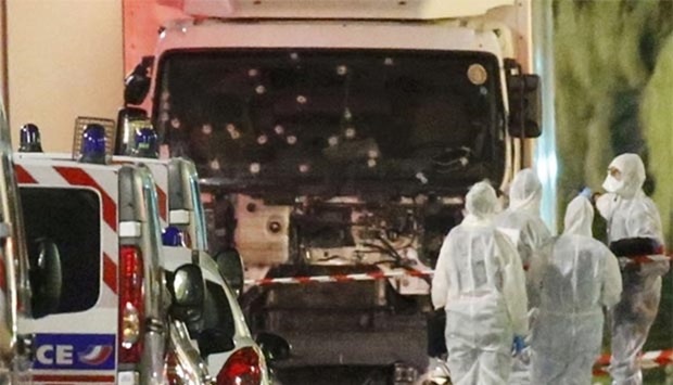 French police forces and forensic officers stand next to a truck on Friday that ran into a crowd celebrating the Bastille Day national holiday on the Promenade des Anglais in Nice.
