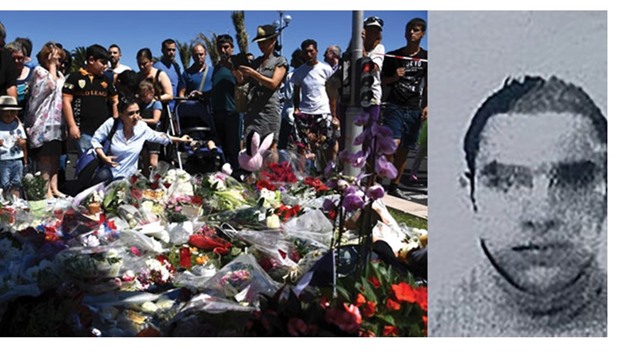People laying flowers in the street of Nice to pay tribute to the victims the day after a gunman smashed a truck into a crowd of revellers celebrating Bastille Day. This image obtained by AFP from a French police source shows a reproduction of the picture on the residence permit of Mohamed Lahouaiej Bouhlel.