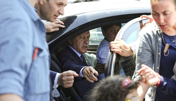 Turkish President Tayyip Erdogan sits inside a car with family members as security officers stand around at Istanbul airport.