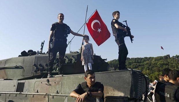 Policemen stand on a military vehicle after troops involved in the coup surrendered on the Bosphorus Bridge in Istanbul on Saturday.