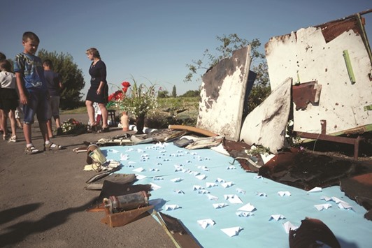 A boy looks at debris from the crash of the flight MH17 next to small paper planes made by local children at the makeshift memorial in Petropavlivka village.