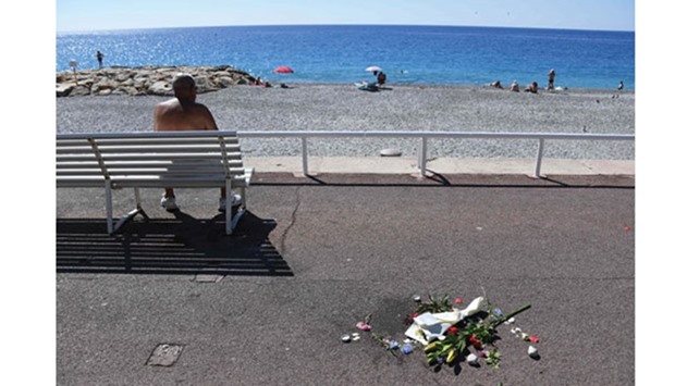 People enjoy the beach yesterday near flowers laid down as a tribute to victims of the deadly Bastille Day attack on the Promenade des Anglais in Nice.
