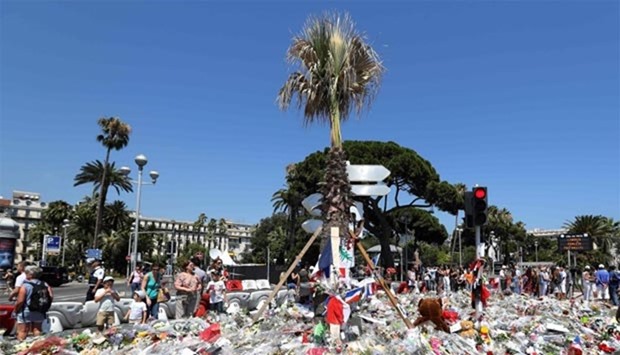 People gather near tributes placed at a makeshift memorial near the Promenade des Anglais in Nice on Monday for the victims of the Bastille Day attack that left 84 dead.