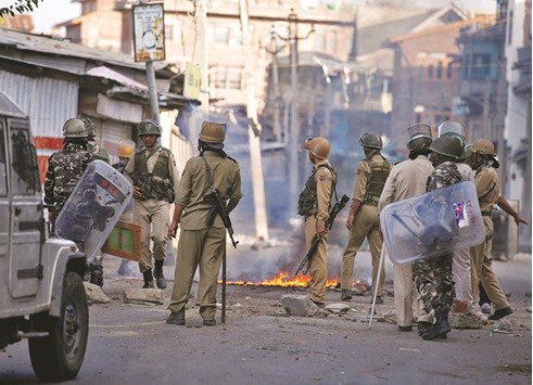 Policemen stand next to a burning handcart set on fire by demonstrators during a protest in Srinagar yesterday.
