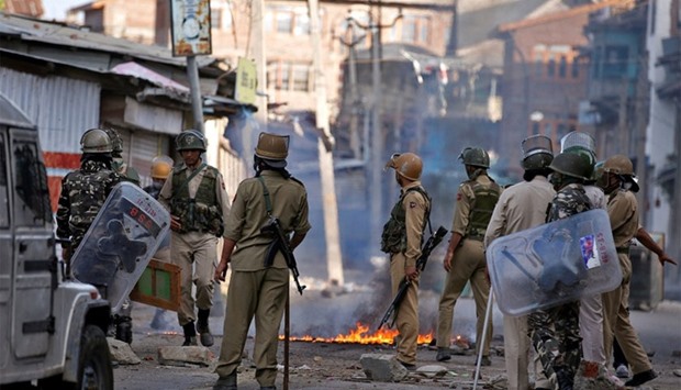 Indian policemen stand next to a burning handcart set on fire by demonstrators during a protest in Srinagar against the recent killings in Kashmir.