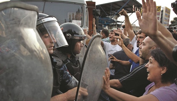 Armenian opposition supporters clash with riot police blocking the streets to Erebuni police station, where gunmen are holding hostages, in Yerevan yesterday. Pro-opposition gunmen are holding four police hostage, officials said, two days after they seized a police building, killing one officer and taking several hostages.